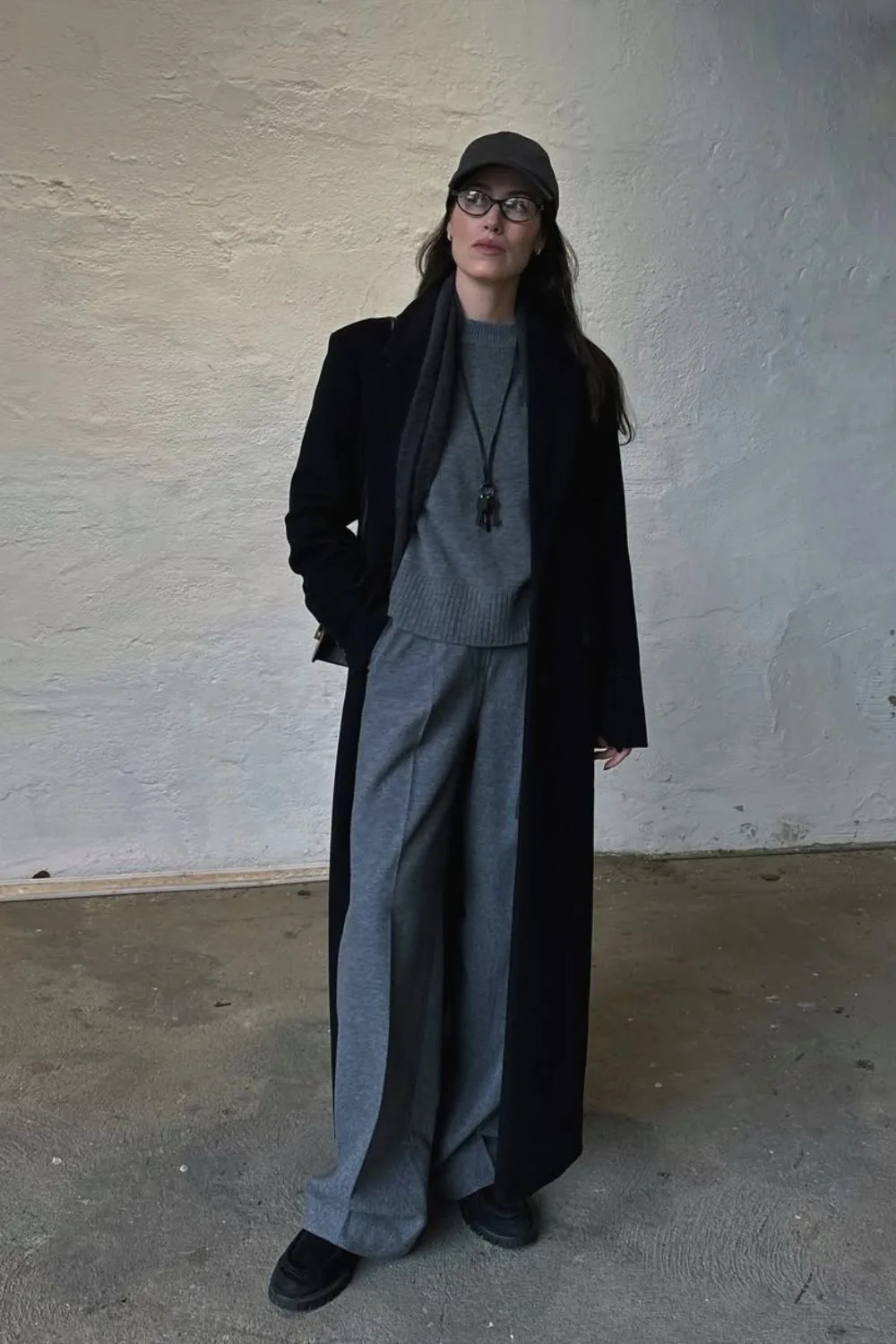 Pull gris épais avec pantalon tailleur gris large, manteau noir et bonnet