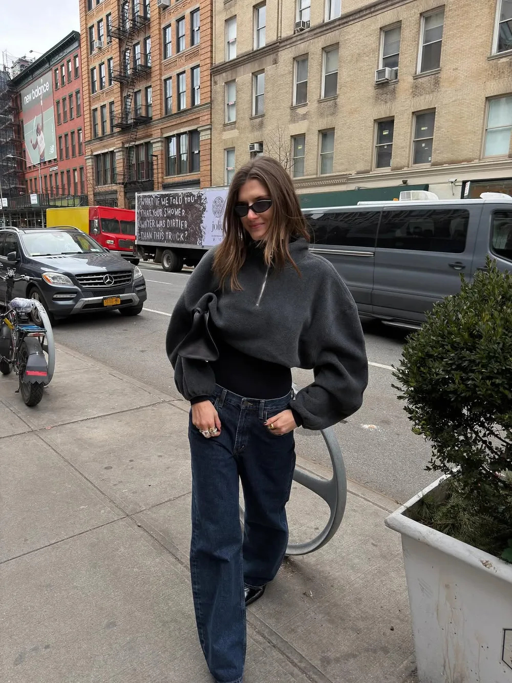Pull gris oversize avec jean bleu foncé large, sac noir et lunettes de soleil