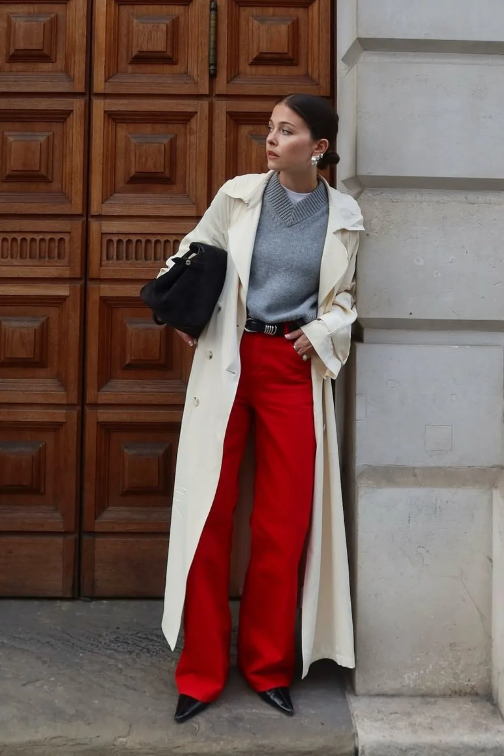 Pull gris sous un trench clair avec pantalon rouge large et bottines noires