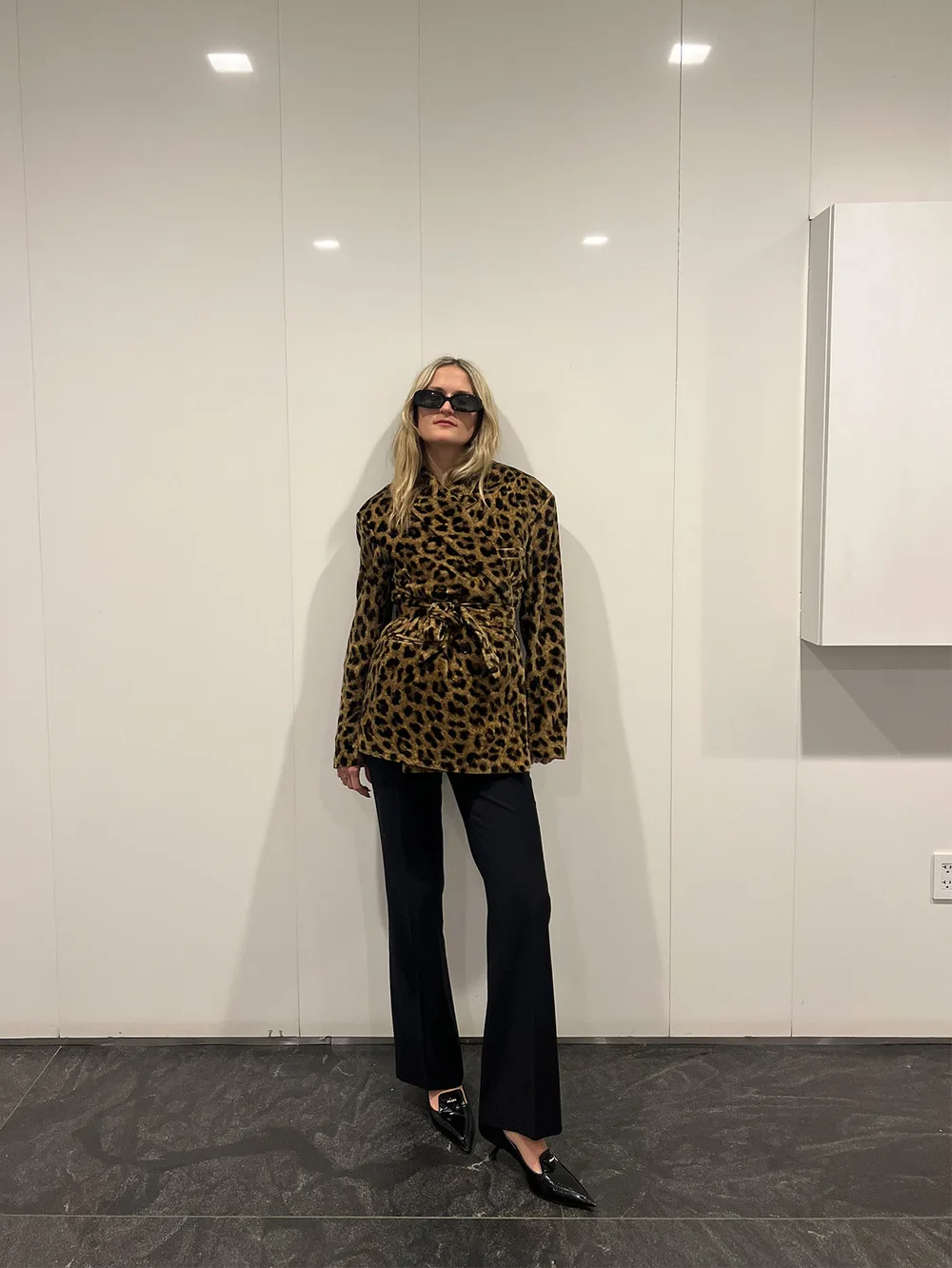 Pull léopard ample porté avec un pantalon noir large et des mocassins