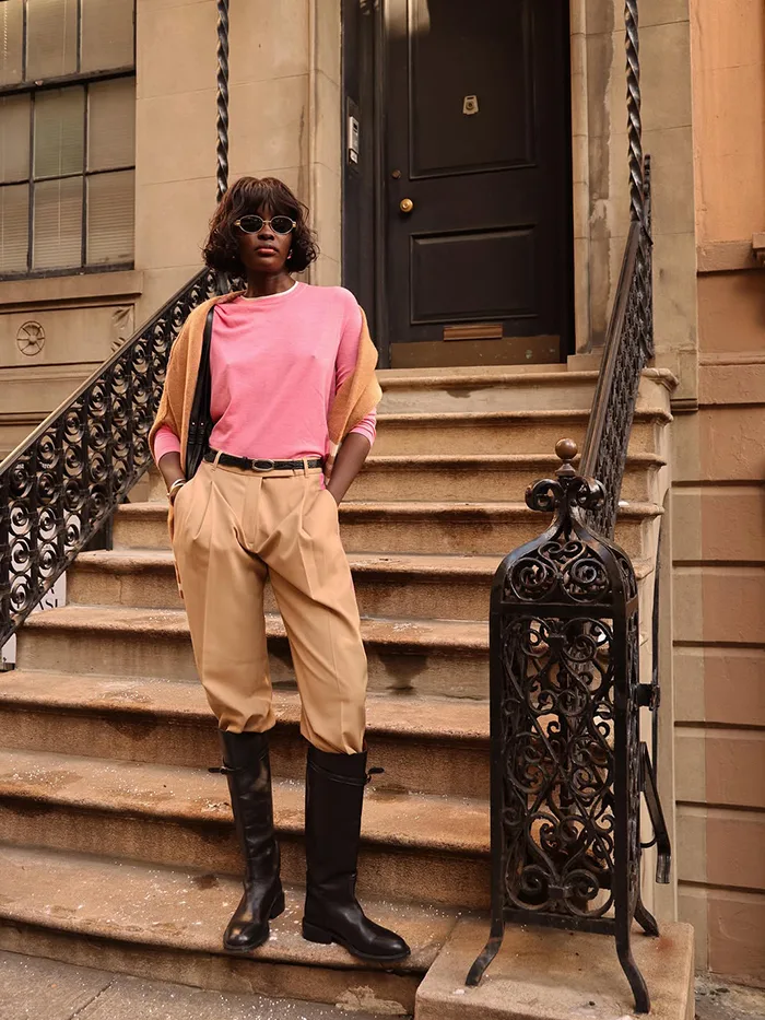 Pull rose avec pantalon beige et bottes noires hautes