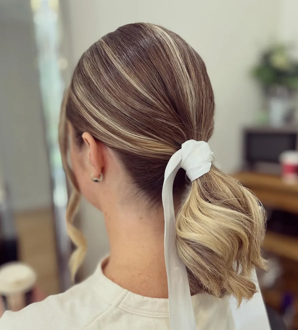 Queue-de-cheval basse avec ruban blanc sur cheveux mi-longs