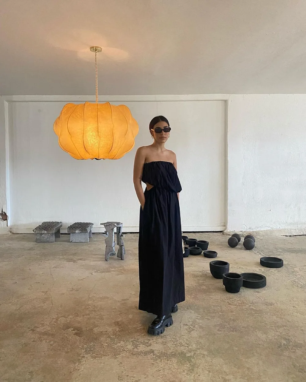 Robe noire longue fluide portée avec des bottes de combat et des lunettes noires