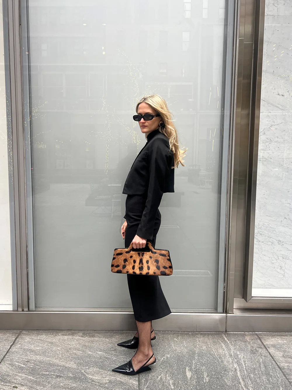 Sac léopard porté avec une veste noire et une jupe midi noire