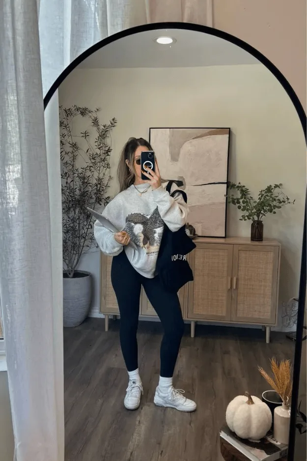 Sweat blanc à imprimé graphique porté avec un legging noir et des baskets blanches