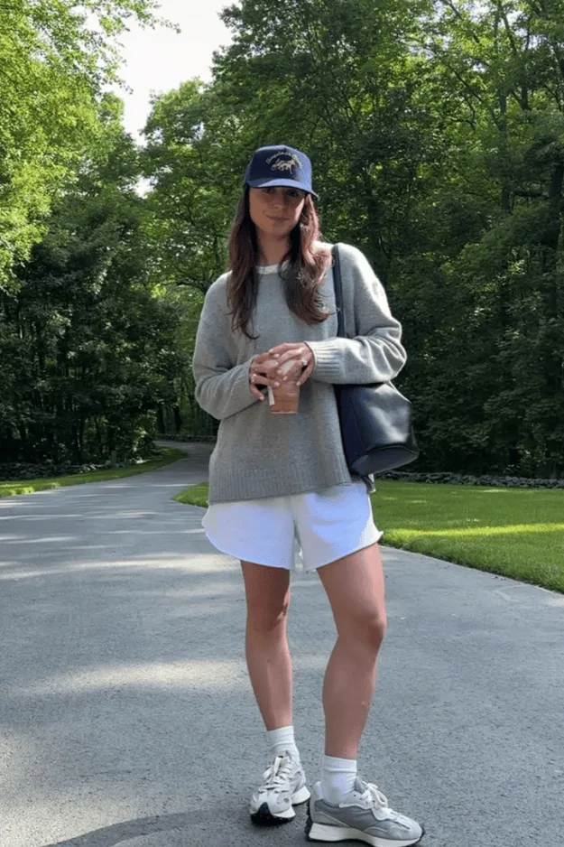 Sweat gris porté avec un short blanc, une casquette et des baskets, en extérieur