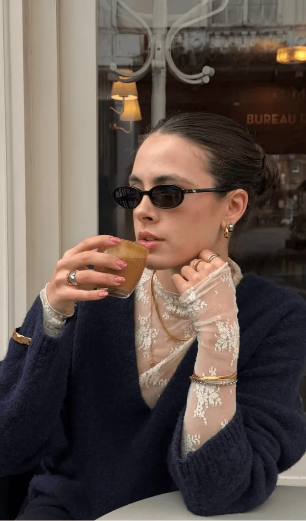 Top transparent brodé porté sous un pull marine épaule dénudée