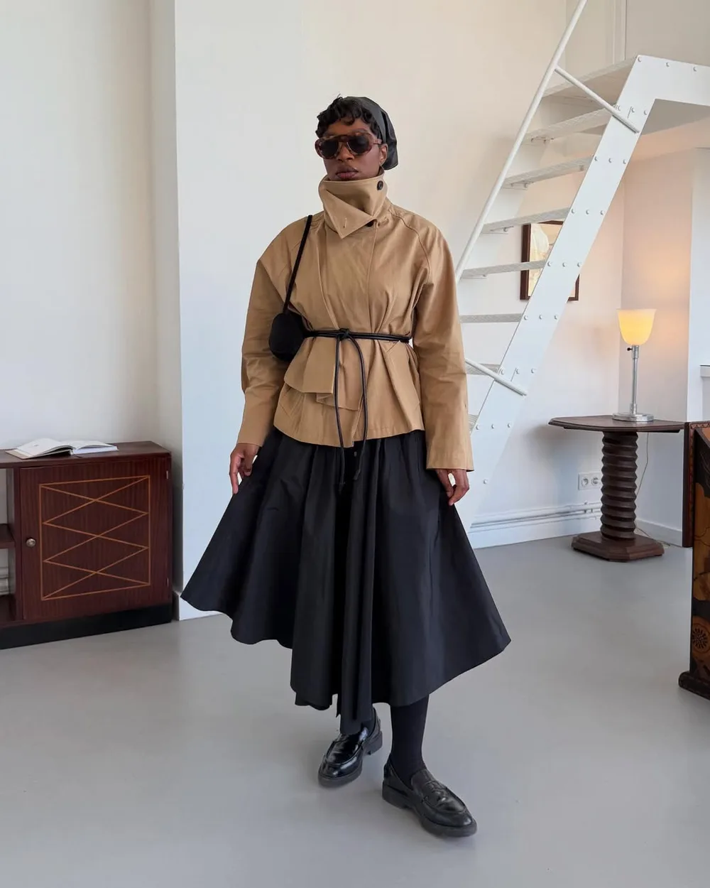Trench court beige à col montant avec jupe midi noire et chaussures épaisses