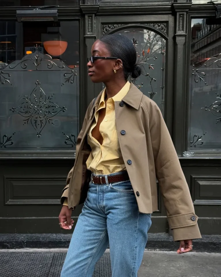 Trench court beige porté avec une chemise jaune et un jean bleu