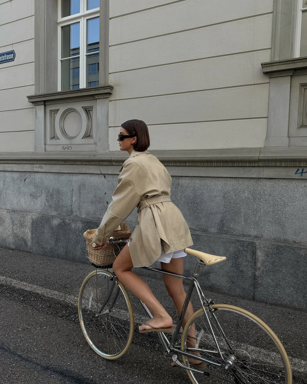 Trench court beige porté sur une longue robe noire avec bottines