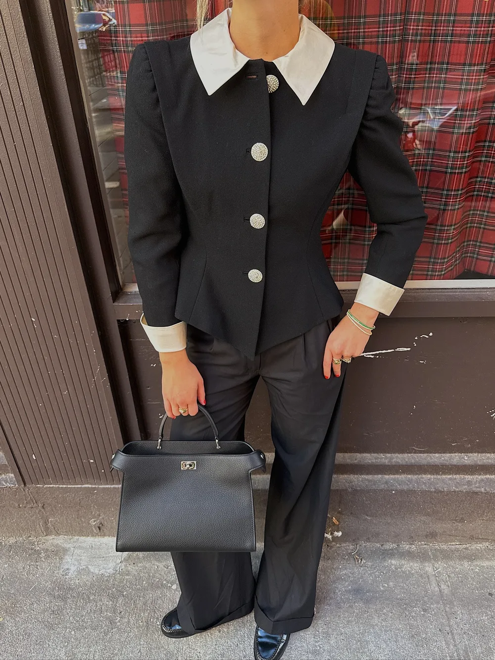 Veste cintrée noire à col blanc portée avec un pantalon de tailleur et des mocassins