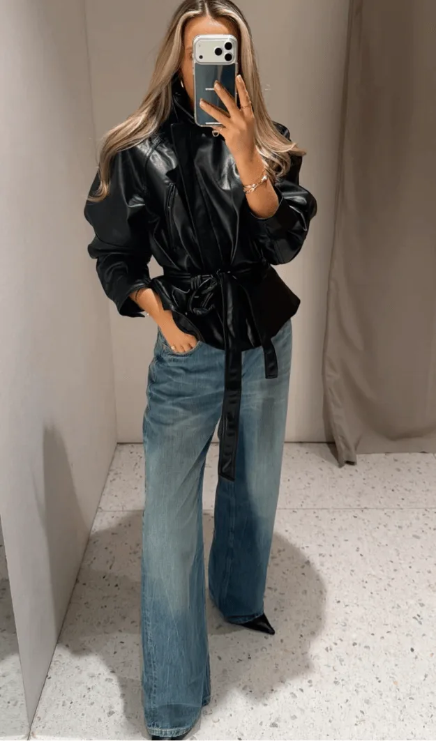 Veste en cuir noire ceinturée à la taille portée avec un jean délavé