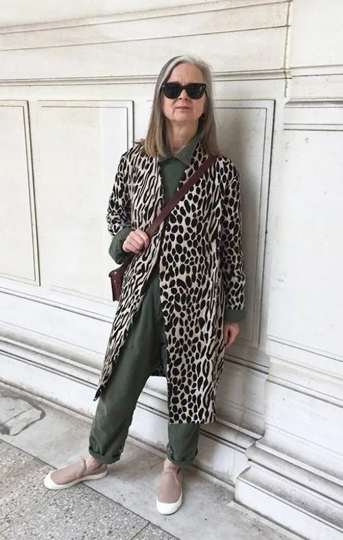 Femme âgée en robe à sequins et béret rouge devant un sapin de Noël