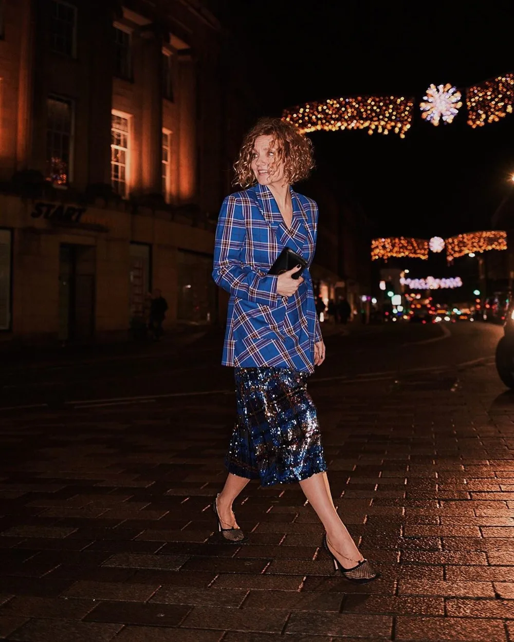 Femme de 60 ans en blazer tartan bleu et jupe à sequins pour Noël