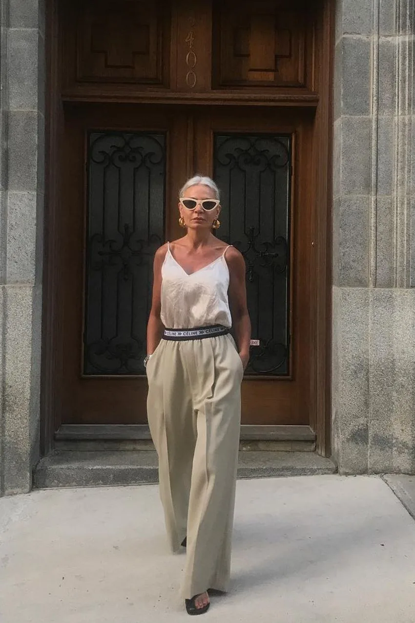 Femme de 60 ans en caraco satiné et pantalon large beige