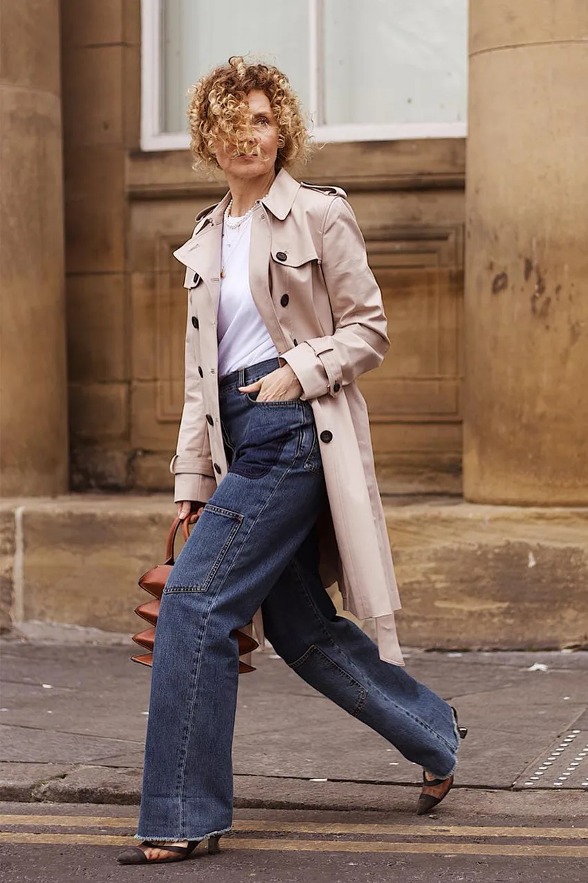 Femme de 60 ans en jean flare avec trench beige classique