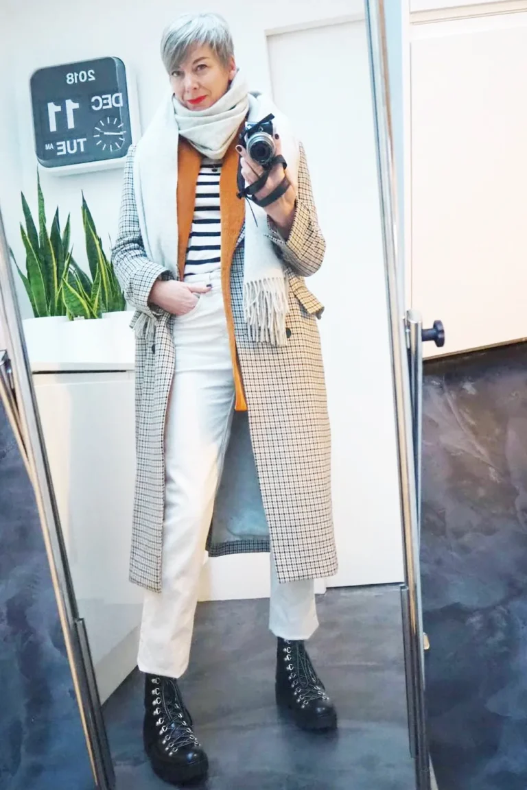 Femme de 60 ans en manteau long à carreaux sur une tenue blanche