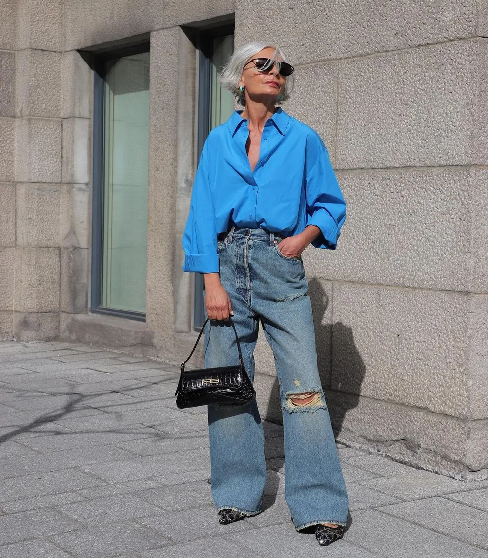 Femme de plus de 60 ans en jean déchiré large et chemise bleu vif