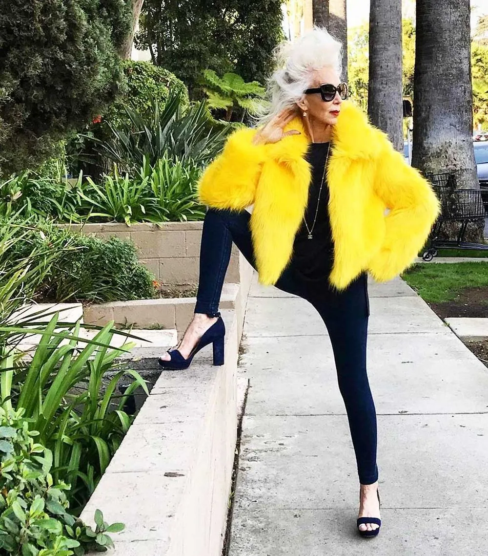 Femme de plus de 60 ans en veste jaune avec pantalon noir et escarpins