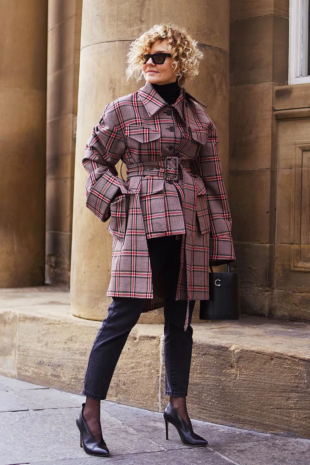 Femme mûre en trench tartan ceinturé avec pantalon noir