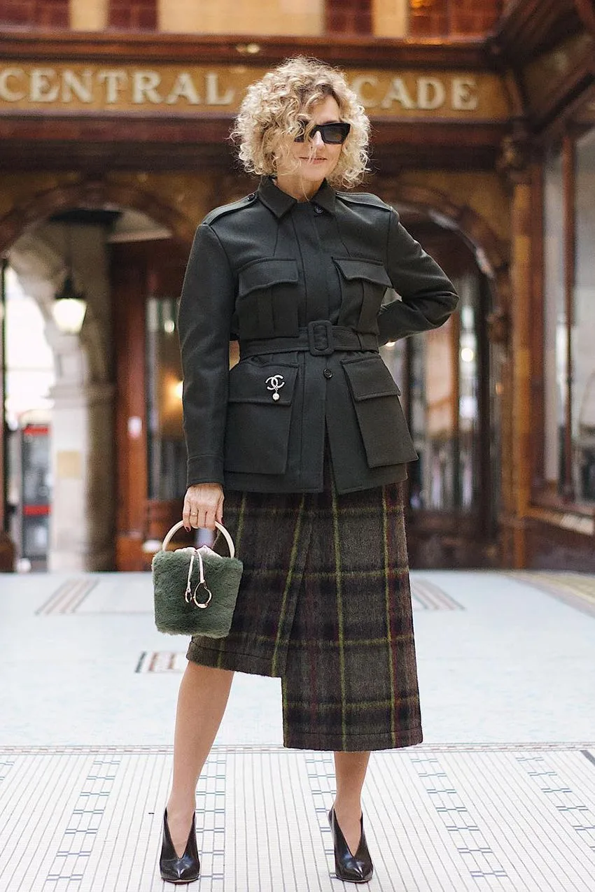Femme mûre en veste saharienne noire et jupe midi tartan
