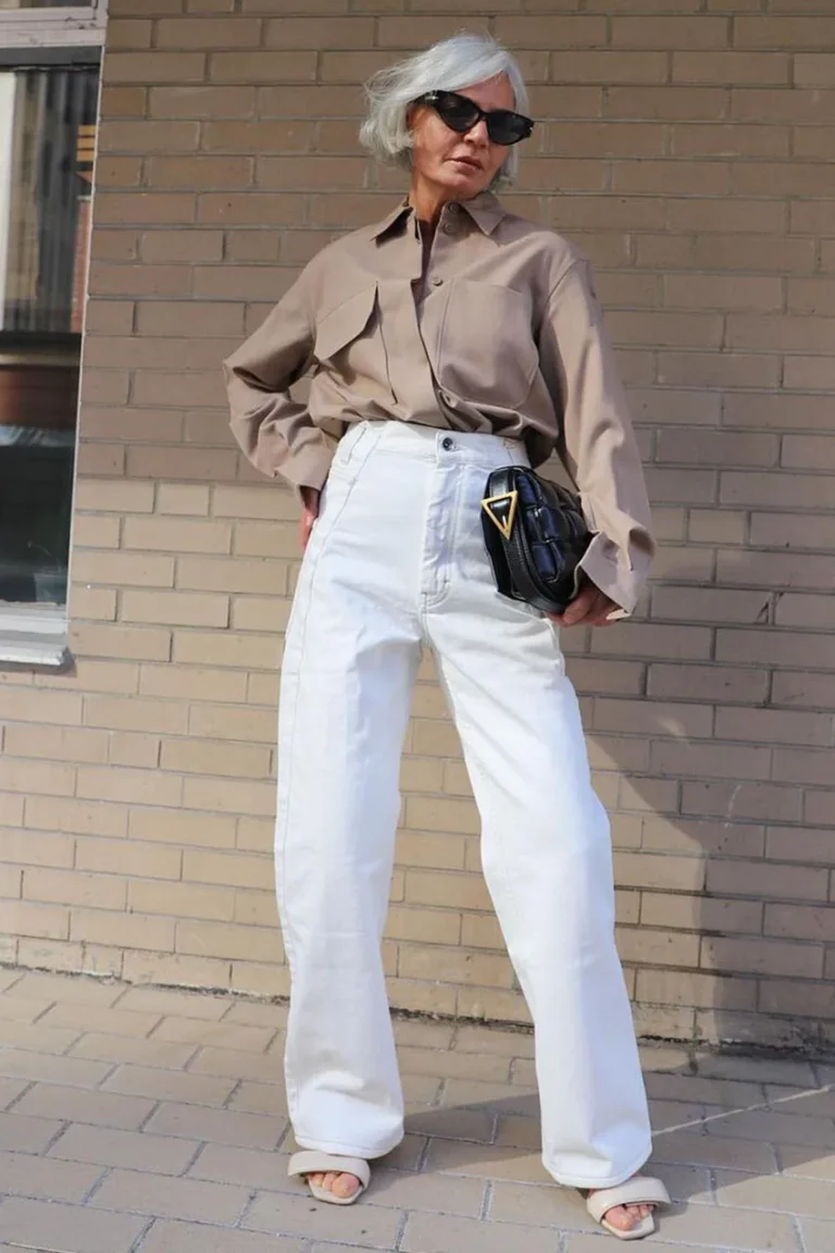 Femme mûre portant une chemise taupe avec un pantalon blanc