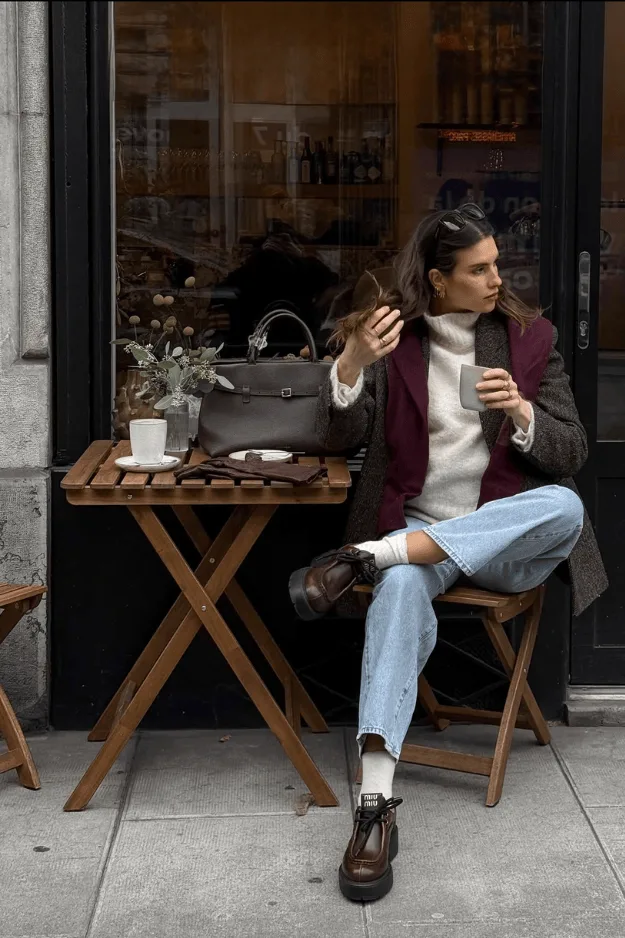 Jean bleu droit avec blazer marron et maille rouge dans un café