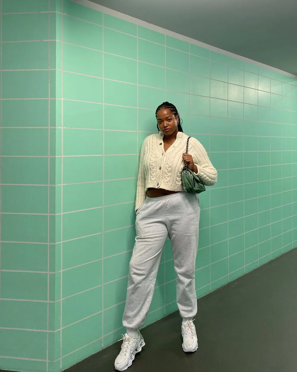Jogging gris porté avec un cardigan crème et un sac vert