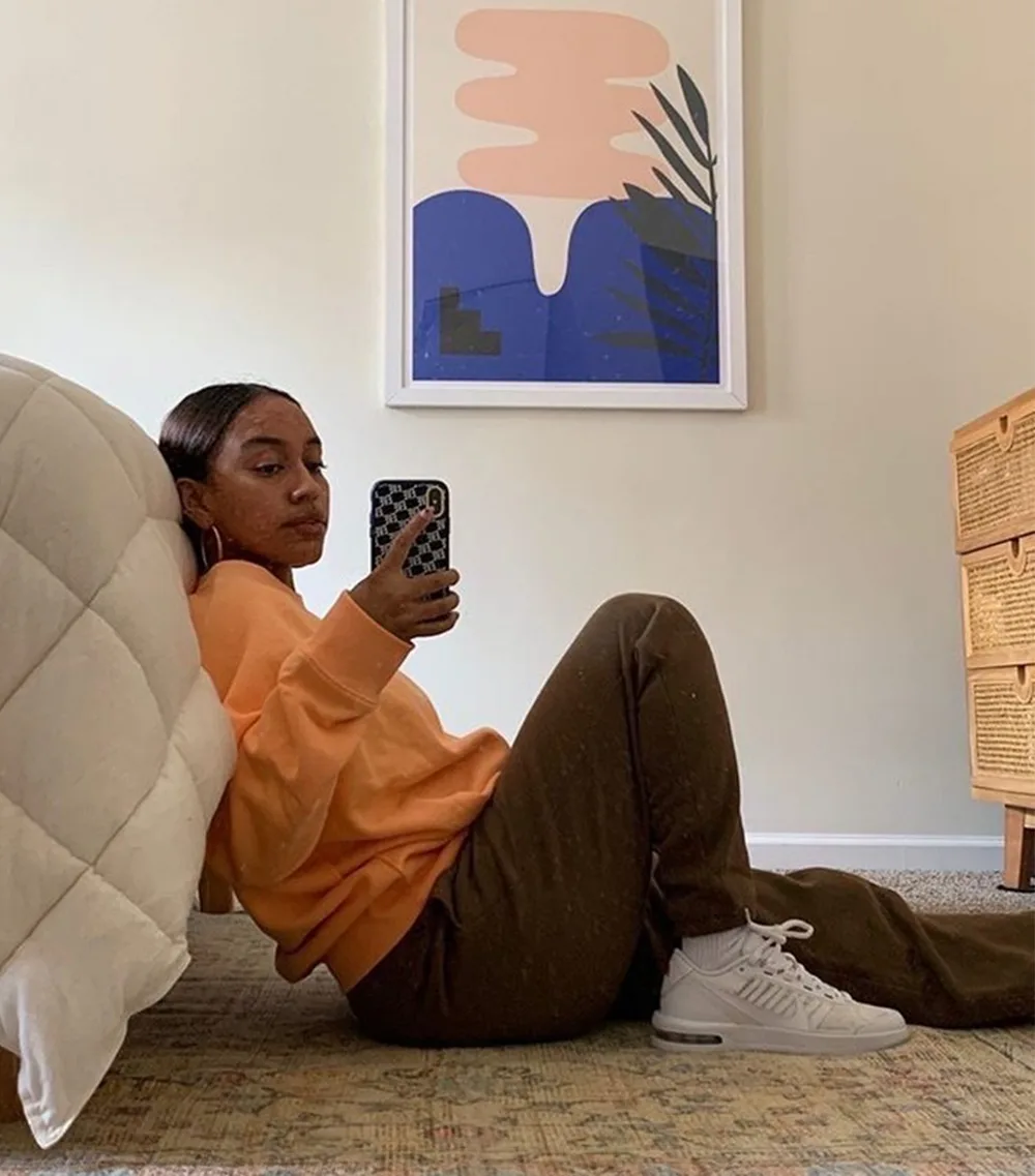 Jogging marron porté avec un sweat orange et des baskets blanches