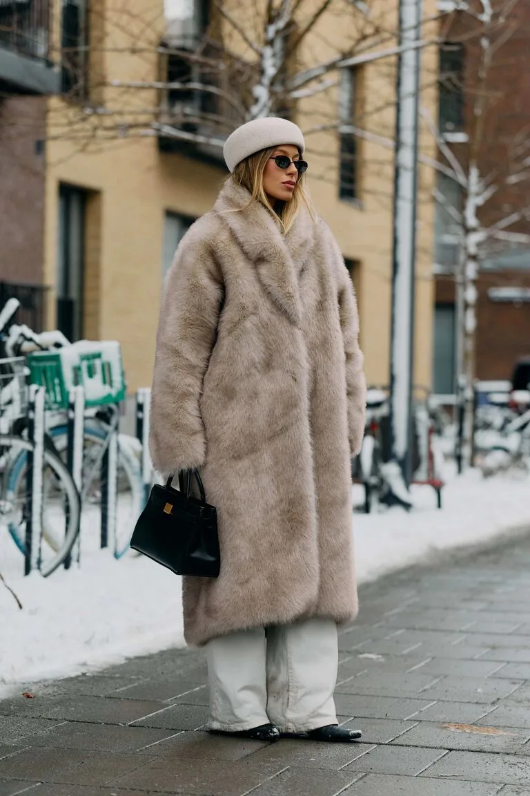 Long manteau en fausse fourrure grège porté dans la neige