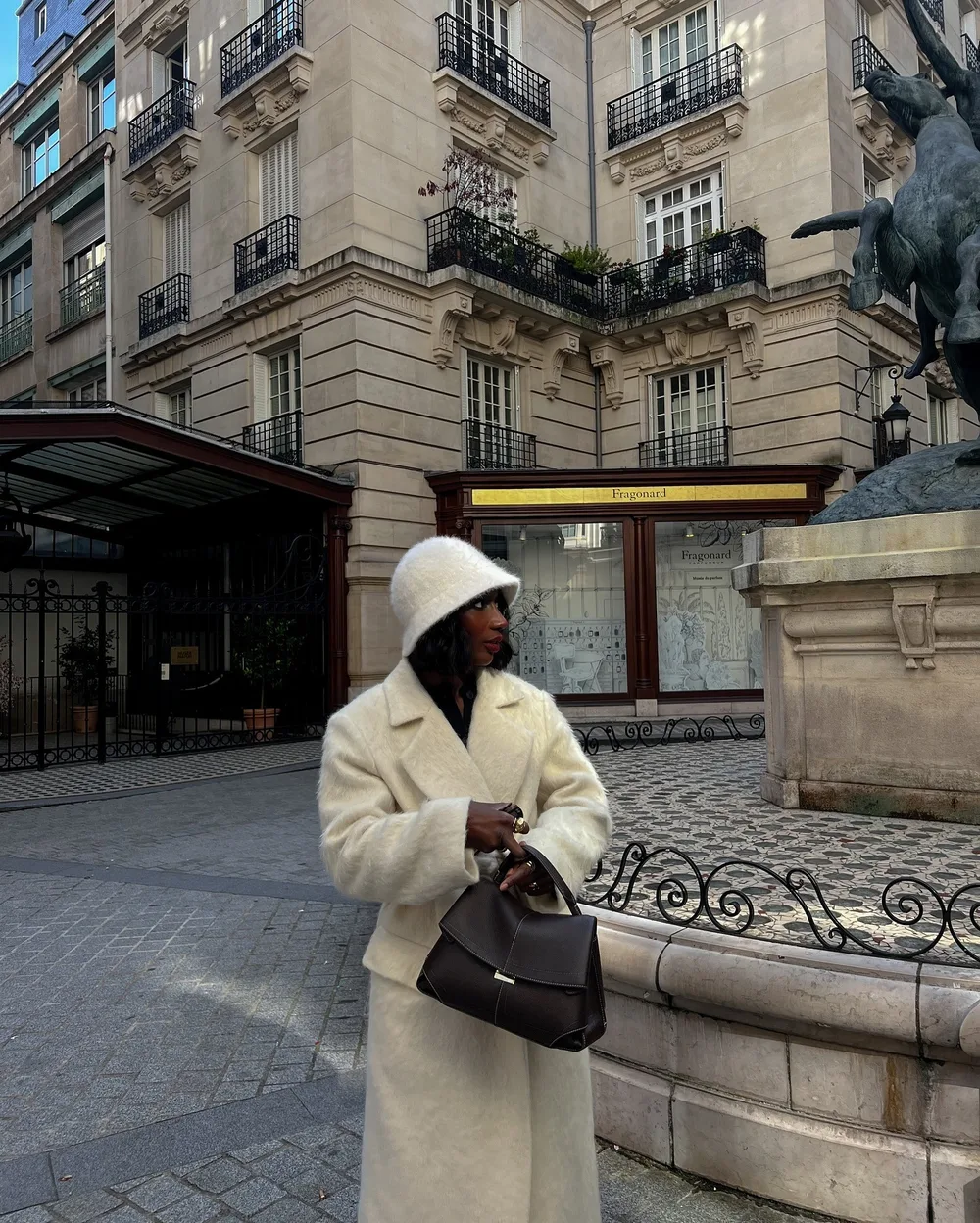 Manteau peignoir ivoire ceinturé porté avec un sac noir
