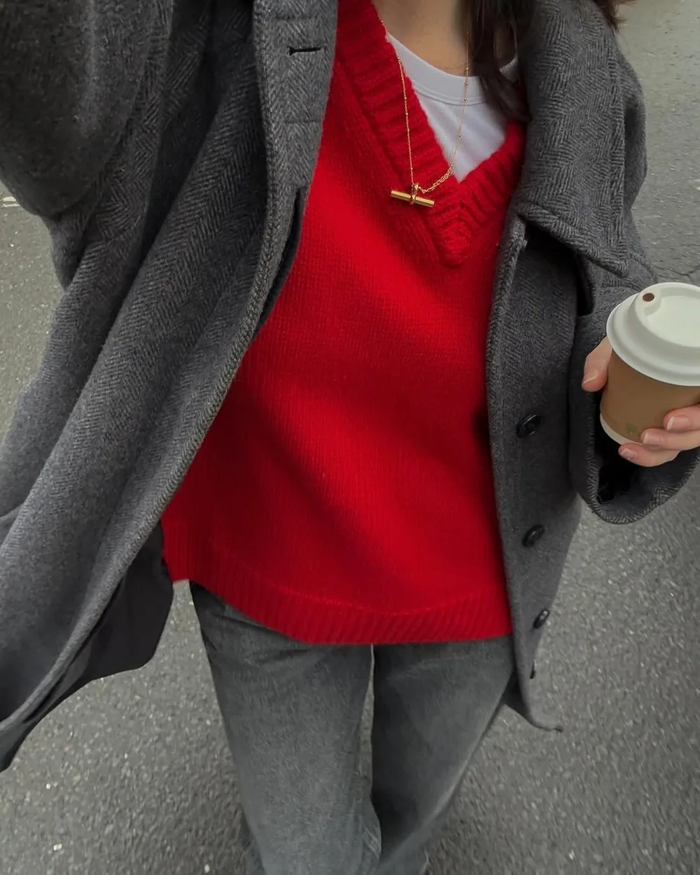 Pull rouge col V sous un manteau gris avec jean gris