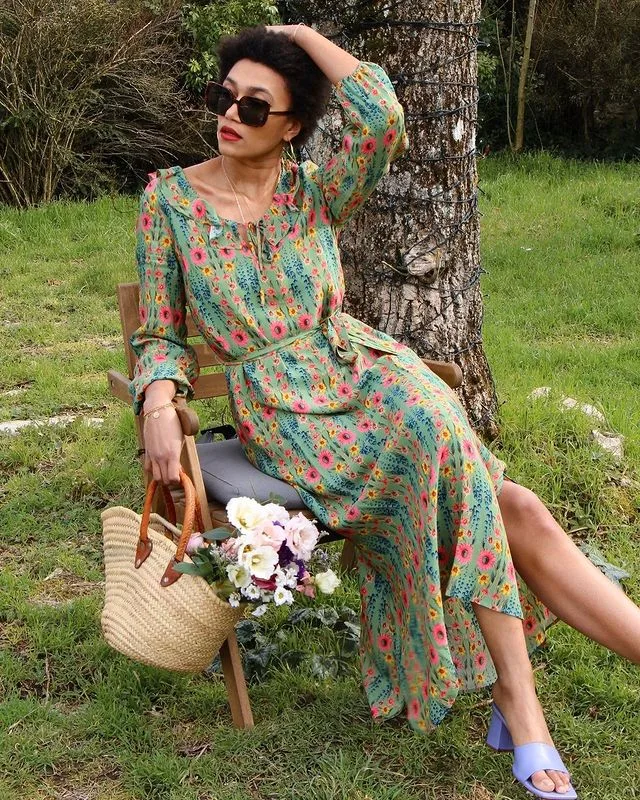 Robe longue fleurie portée avec des bottines cognac dans un jardin anglais