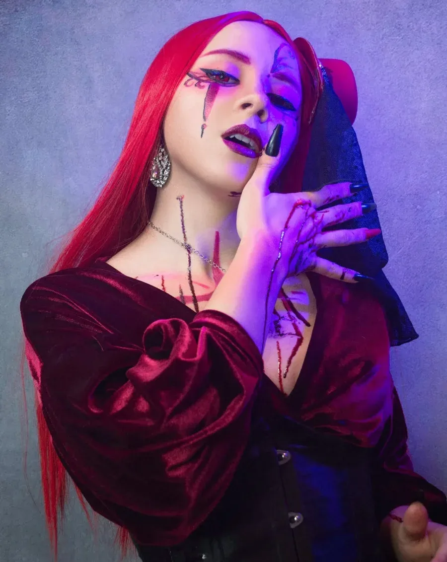 Vampire glamour en robe de velours bordeaux sous des lumières violettes