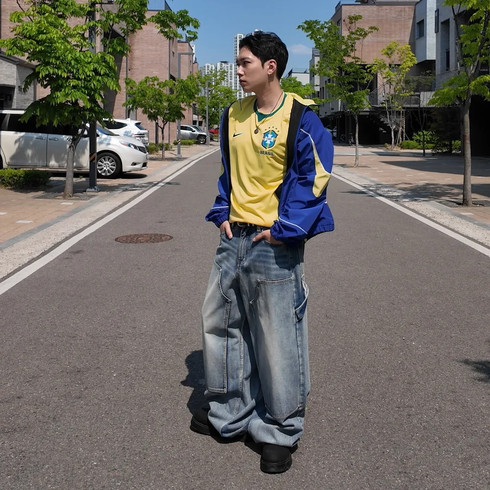 Veste Brésil bleue portée ouverte sur un maillot jaune et un jean baggy