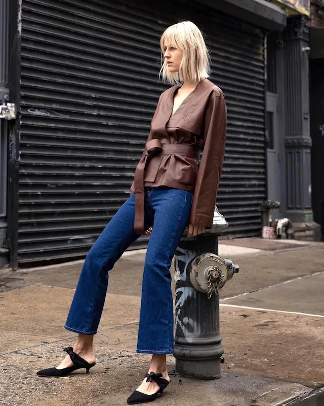 Veste marron ceinturée portée avec un jean évasé et des chaussures noires
