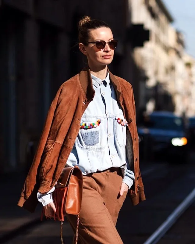 Veste marron posée sur une chemise en jean et un pantalon clair
